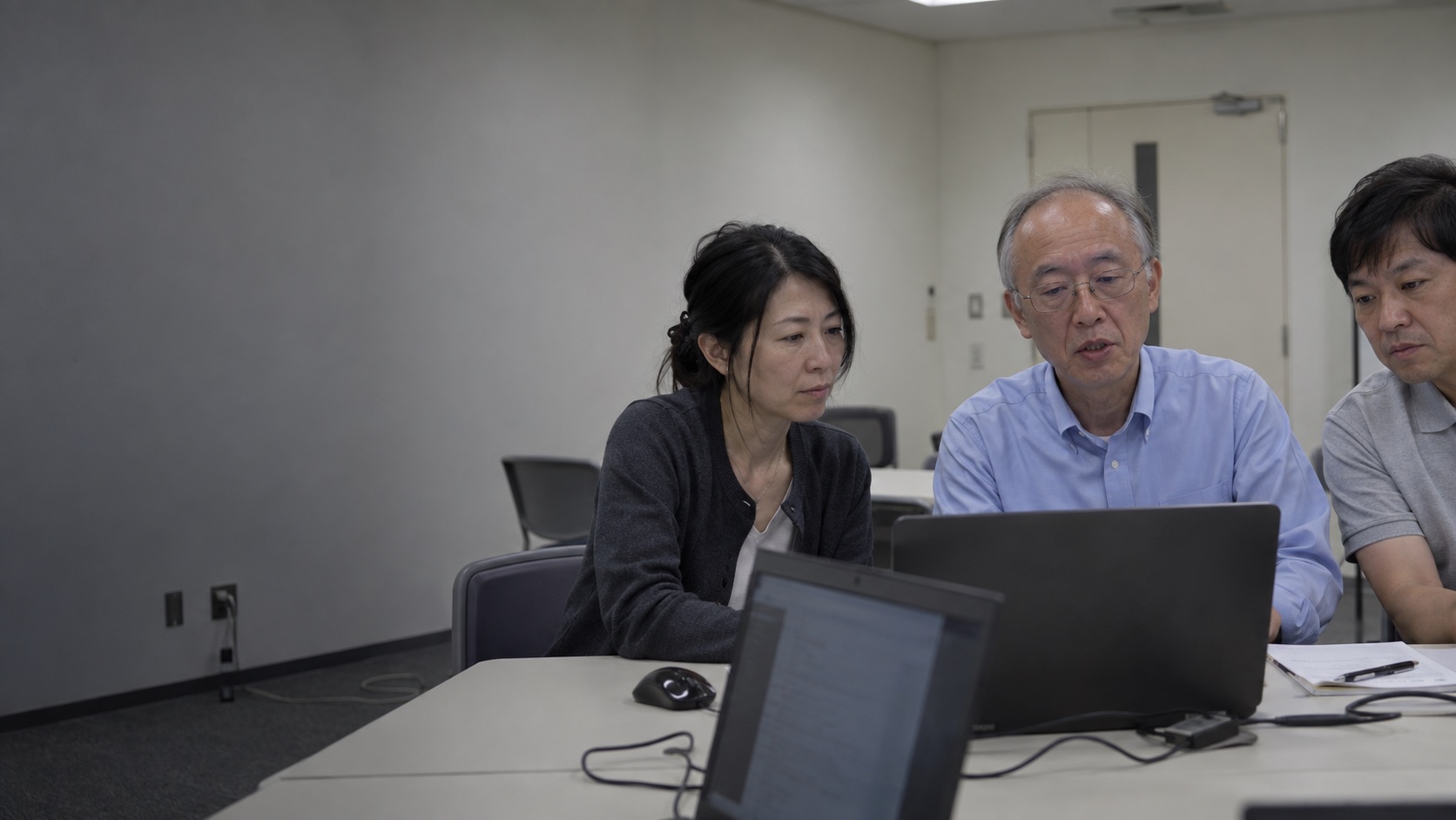 会議室で医師たちがパソコンを囲んで話し合うイメージ